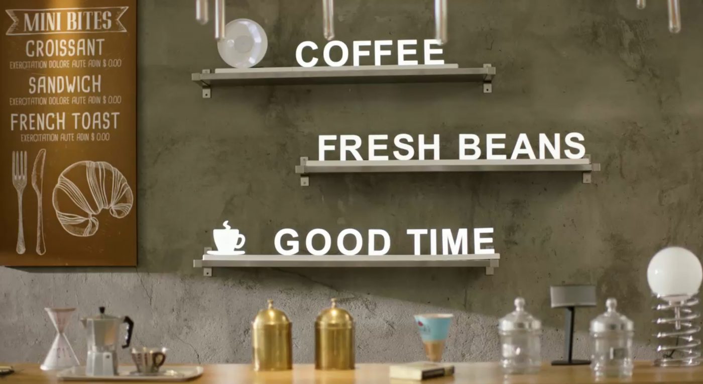 LED-bokstäver som bildar orden COFFEE, FRESH BEANS och GOOD TIMES på vägghyllor i ett kafé