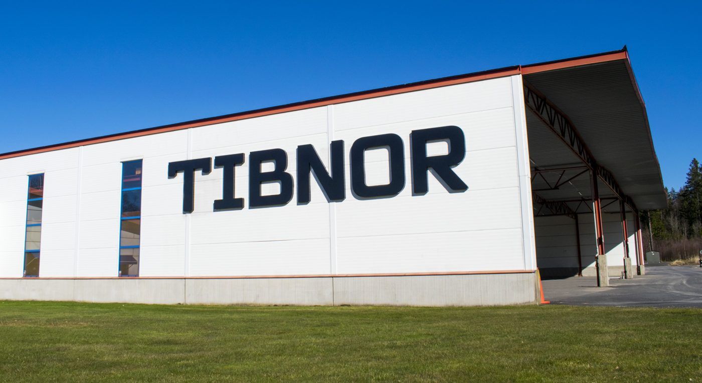 TIBNOR-skylt på vitmålad fastighet mot blå himmel