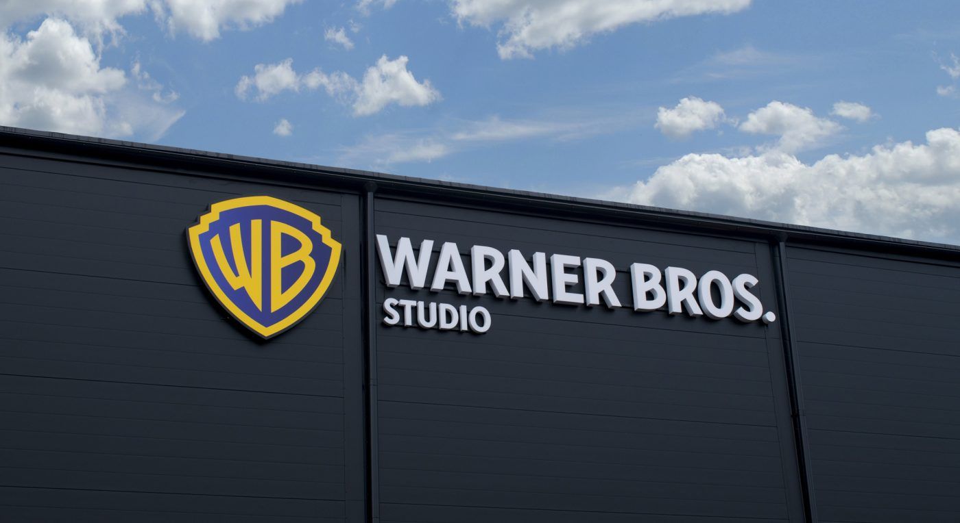 Stor grå fastighet i Göteborg med fasadskyltar och ljuslådor för Warner Bros. Blå himmel med vita moln i bakgrunden