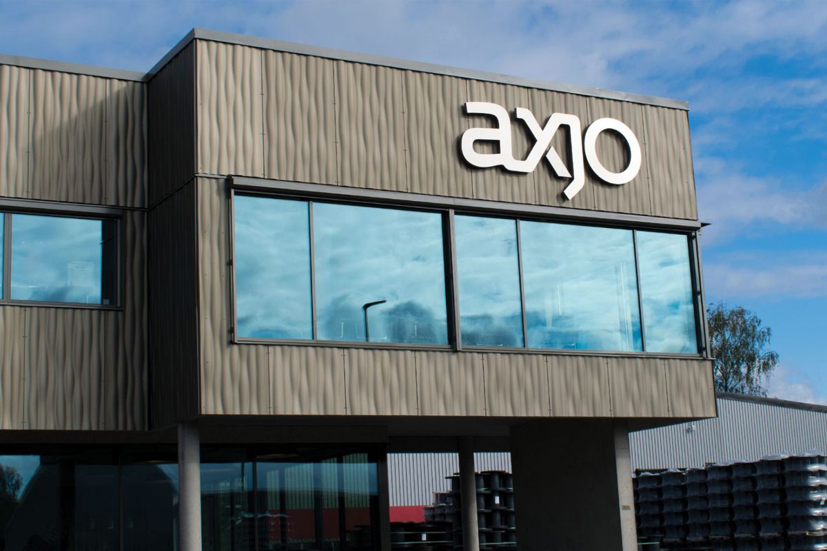 Modern nybyggd mörkgrå fastighet med AXJO-fasadskylt, klarblå himmel i bakgrunden