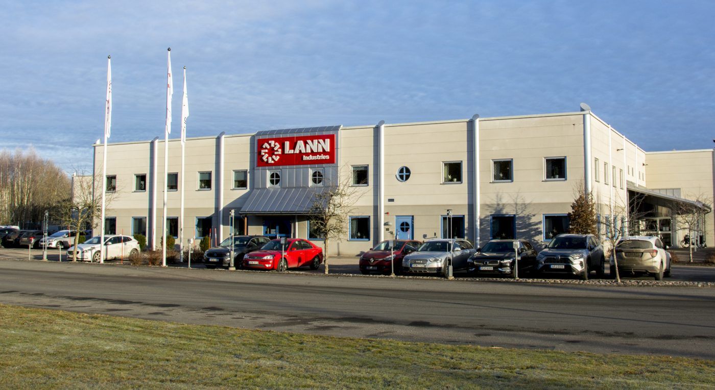 Lann Industries fasadskylt med vita LED-bokstäver monterade på brunröda aluminiumplåtar, fäst på en fastighet med kassettbockade aluminiumplåtar i fasaden, designad och installerad av EpicSign AB