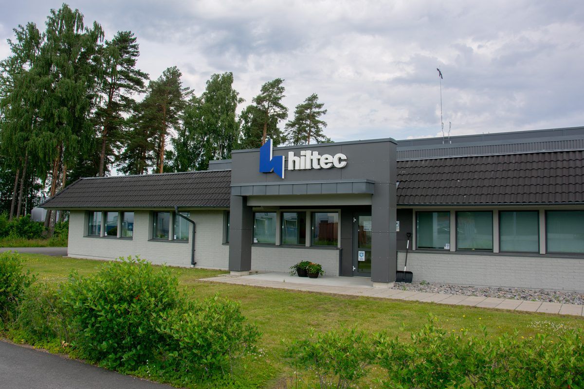 Hiltecs logotyp ovanför huvudentrén till en låg byggnad med gräsmatta framför.