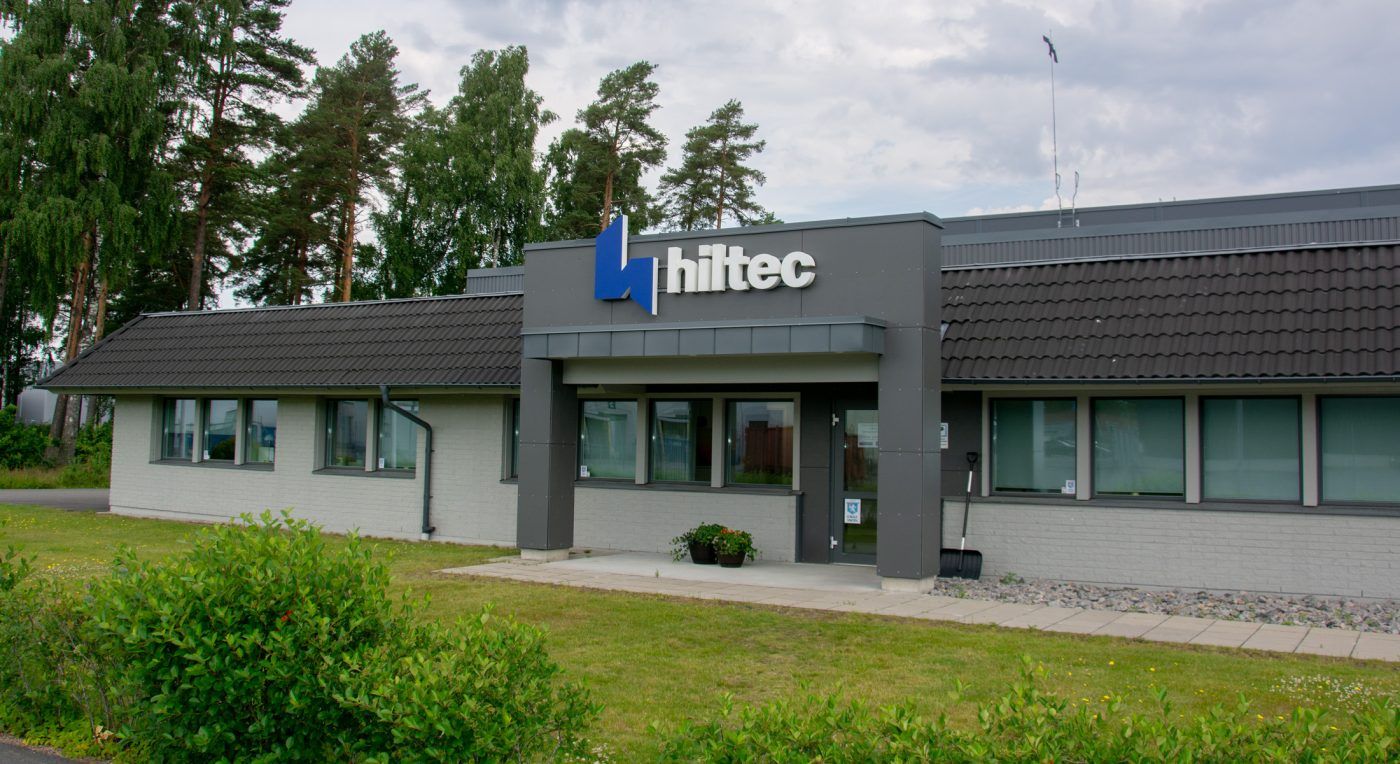 Hiltecs blå symbol och vita bokstäver på ett grått skyltstativ ovanför huvudentrén.