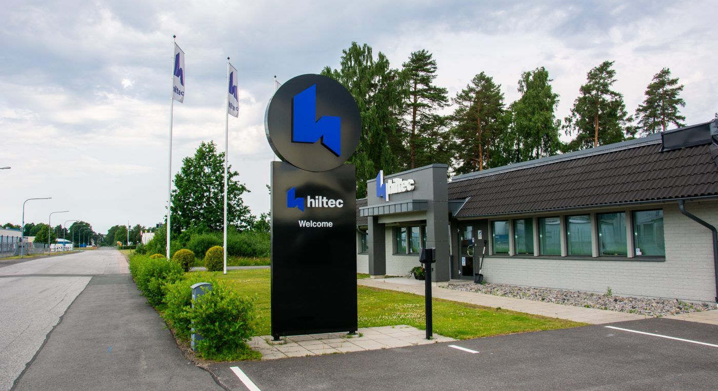 Svart pylonskylt med Hiltecs blå logotyp vid infarten till anläggningen i Gislaved.